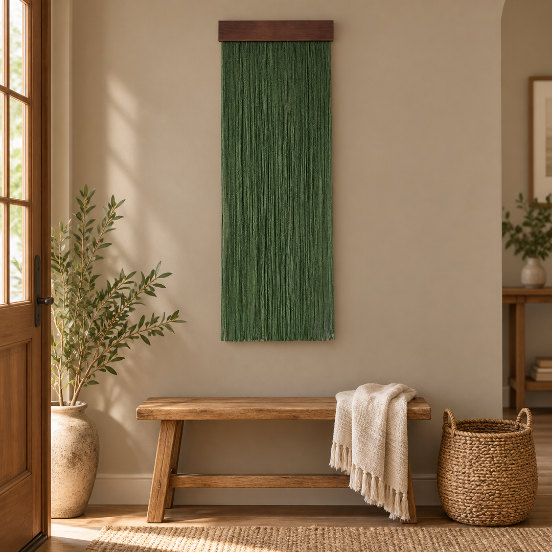 Green fringe wall hanging above a rustic bench and basket in an entry hall