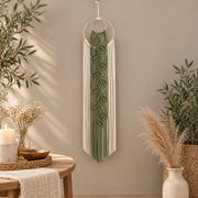 Narrow leaf vine wall hanging beside a round table with candles and pampas