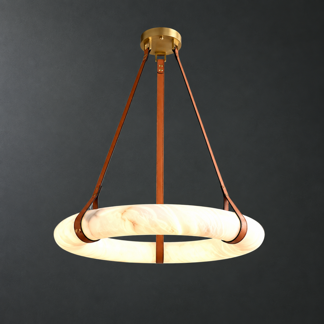 Illuminated alabaster ring chandelier with brown leather straps and brass hardware against a dark gray background.