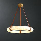 Illuminated alabaster ring chandelier with brown leather straps and brass hardware against a dark gray background.