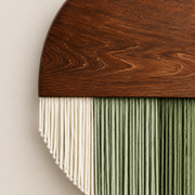 Close view of dark wood grain meeting the cream and green fringe below it