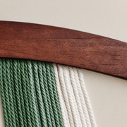 Close view of green and cream twisted rope against the curved dark wood