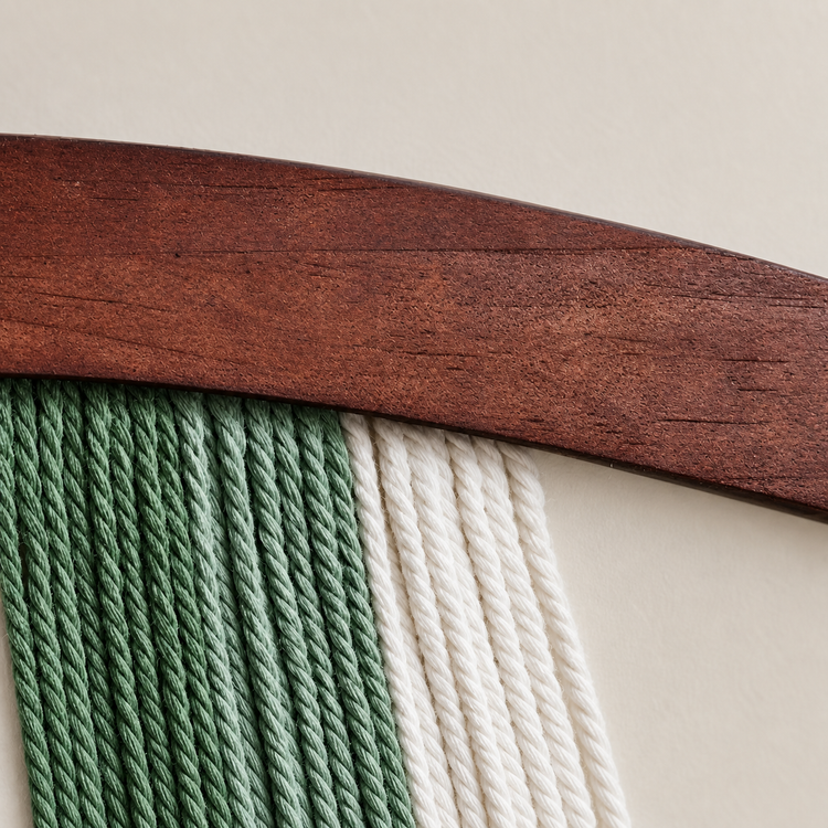Close view of green and cream twisted rope against the curved dark wood