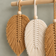 Close view of a tan and a cream macrame leaf showing the combed fringe and bead
