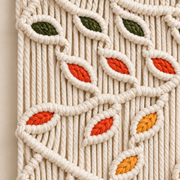 Close view of knotted green, red and mustard leaves worked into cream cord