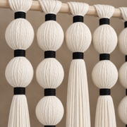 Close view of cream wound yarn spheres joined by narrow black yarn bindings