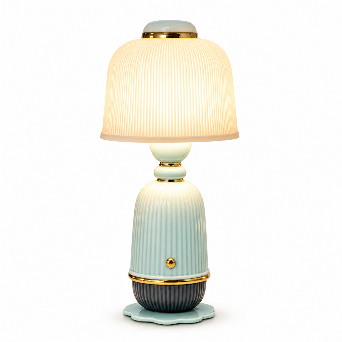 A table lamp with a ribbed ceramic body in pale aqua and dark gray, featuring gold-tone metal trim and a glowing pleated shade, shown on a white background.
