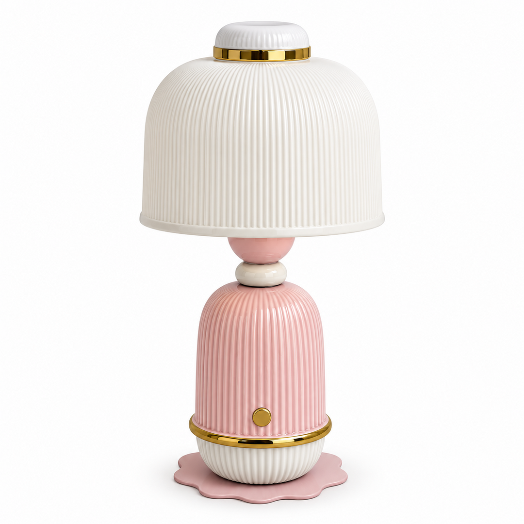 A decorative table lamp with a ribbed white dome shade, a pink ribbed base, and gold metallic accents, shown on a plain white background.