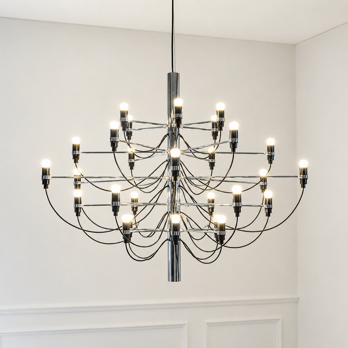 Modern chandelier hanging in a room with white walls and a white door.