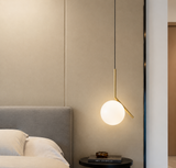 Modern pendant light hanging above a bed in a bedroom setting