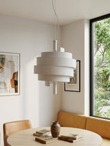 Modern white pendant light hanging above a dining table with books and a vase.