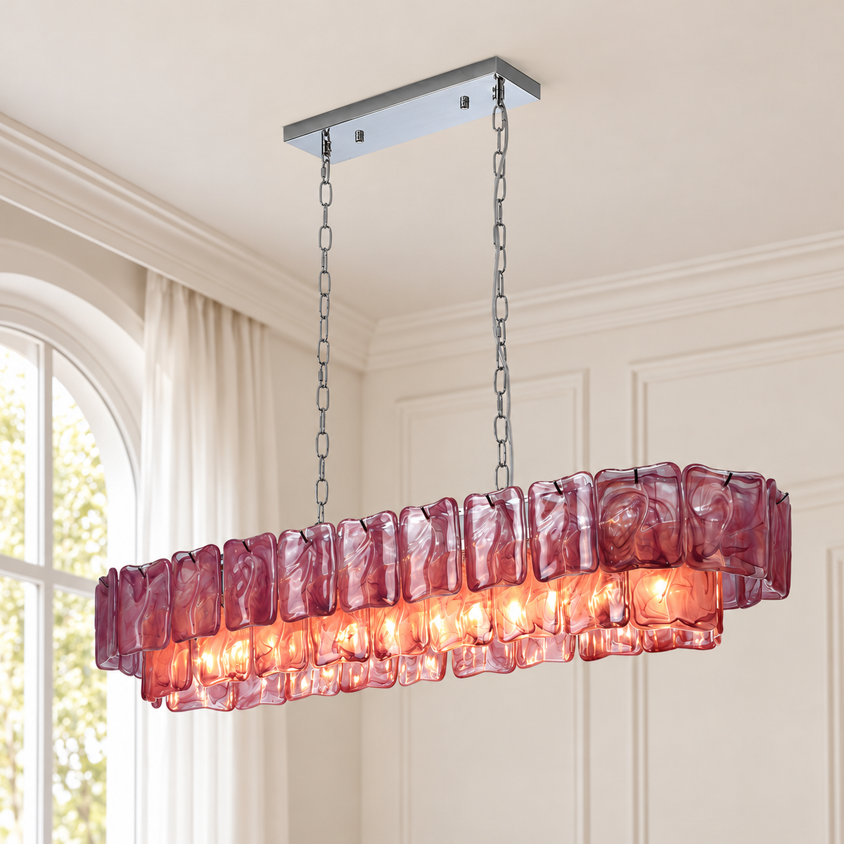 A linear chandelier with rippled purple glass panels and silver chains glows beside an arched window in a cream room.