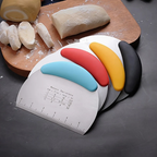 Four bench scrapers with coloured handles on a wooden board beside portioned dough