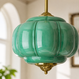Green glass pendant light with gold accents in a room setting