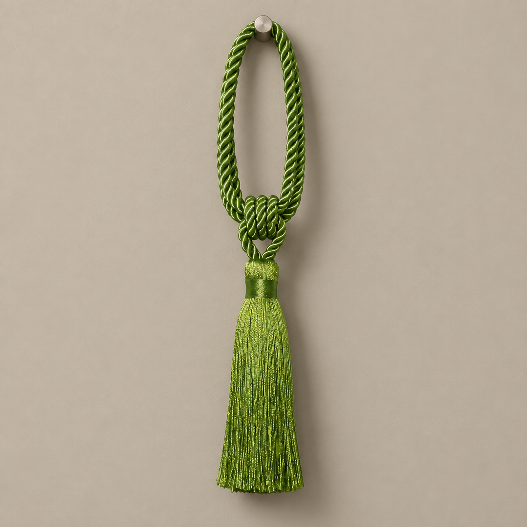 A bright green ceremonial tassel with a braided cord loop and a matching tassel, hanging against a solid taupe background.