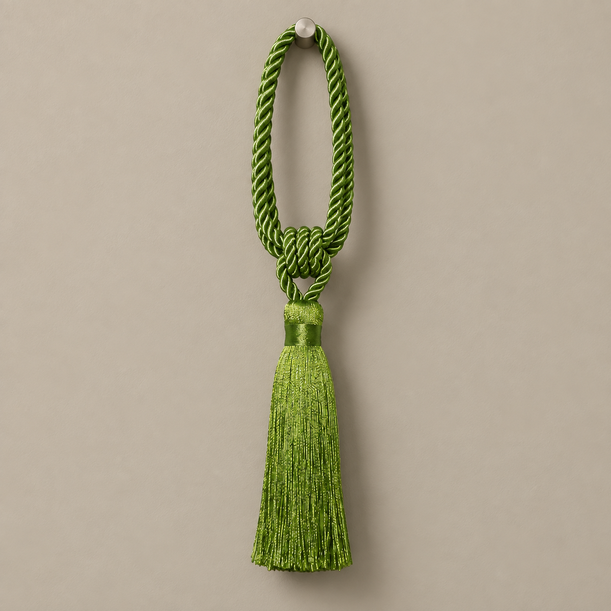 A bright green ceremonial tassel with a braided cord loop and a matching tassel, hanging against a solid taupe background.