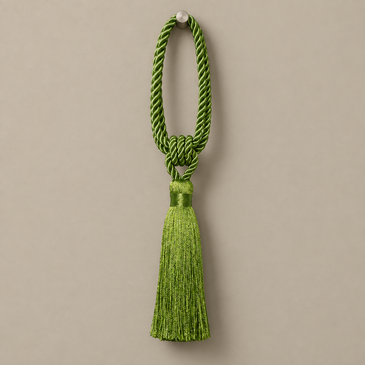 A bright green ceremonial tassel with a braided cord loop and a matching tassel, hanging against a solid taupe background.