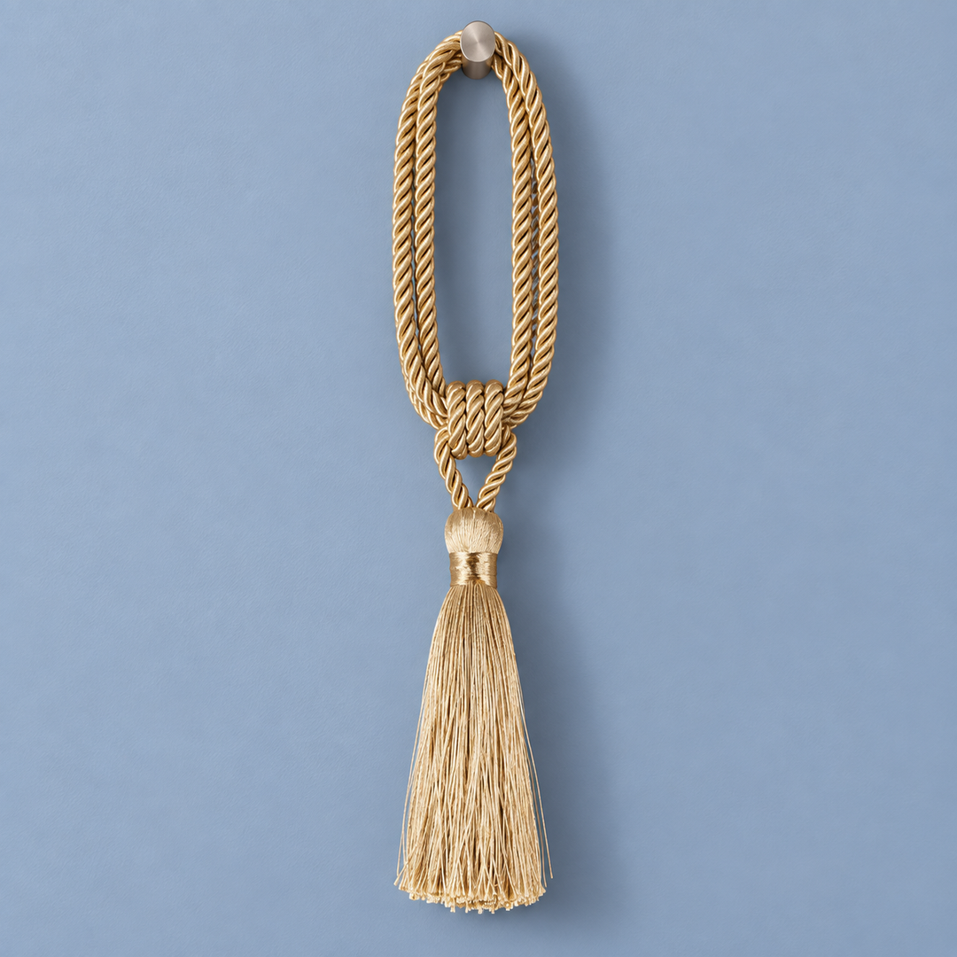 A decorative gold cord tassel ornament with a knotted loop and a long fringe tassel, shown against a solid blue background.
