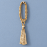 A decorative gold cord tassel ornament with a knotted loop and a long fringe tassel, shown against a solid blue background.