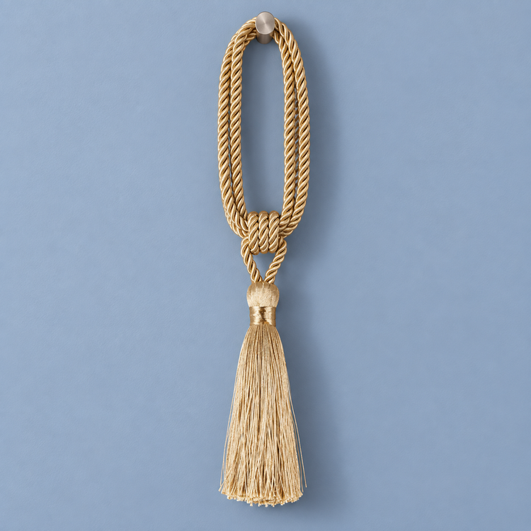 A decorative gold cord tassel ornament with a knotted loop and a long fringe tassel, shown against a solid blue background.