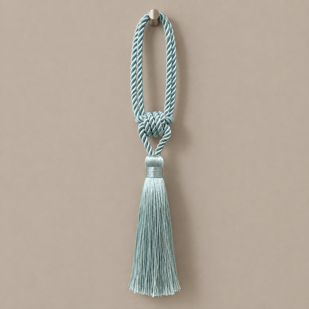 A light blue-green twisted rope tassel with a decorative knot and a matching tassel, hanging from a small metal hook against a solid beige background.