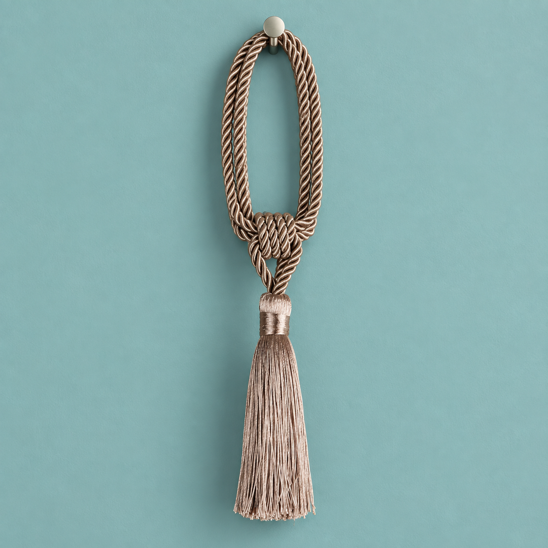 A decorative tassel with a knotted braided cord loop and a long fringed tassel, hanging against a solid teal background.