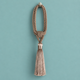 A decorative tassel with a knotted braided cord loop and a long fringed tassel, hanging against a solid teal background.