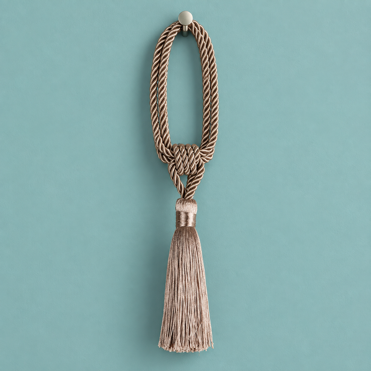 A decorative tassel with a knotted braided cord loop and a long fringed tassel, hanging against a solid teal background.