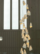 Modern chandelier with glass shades hanging in a room with large windows.