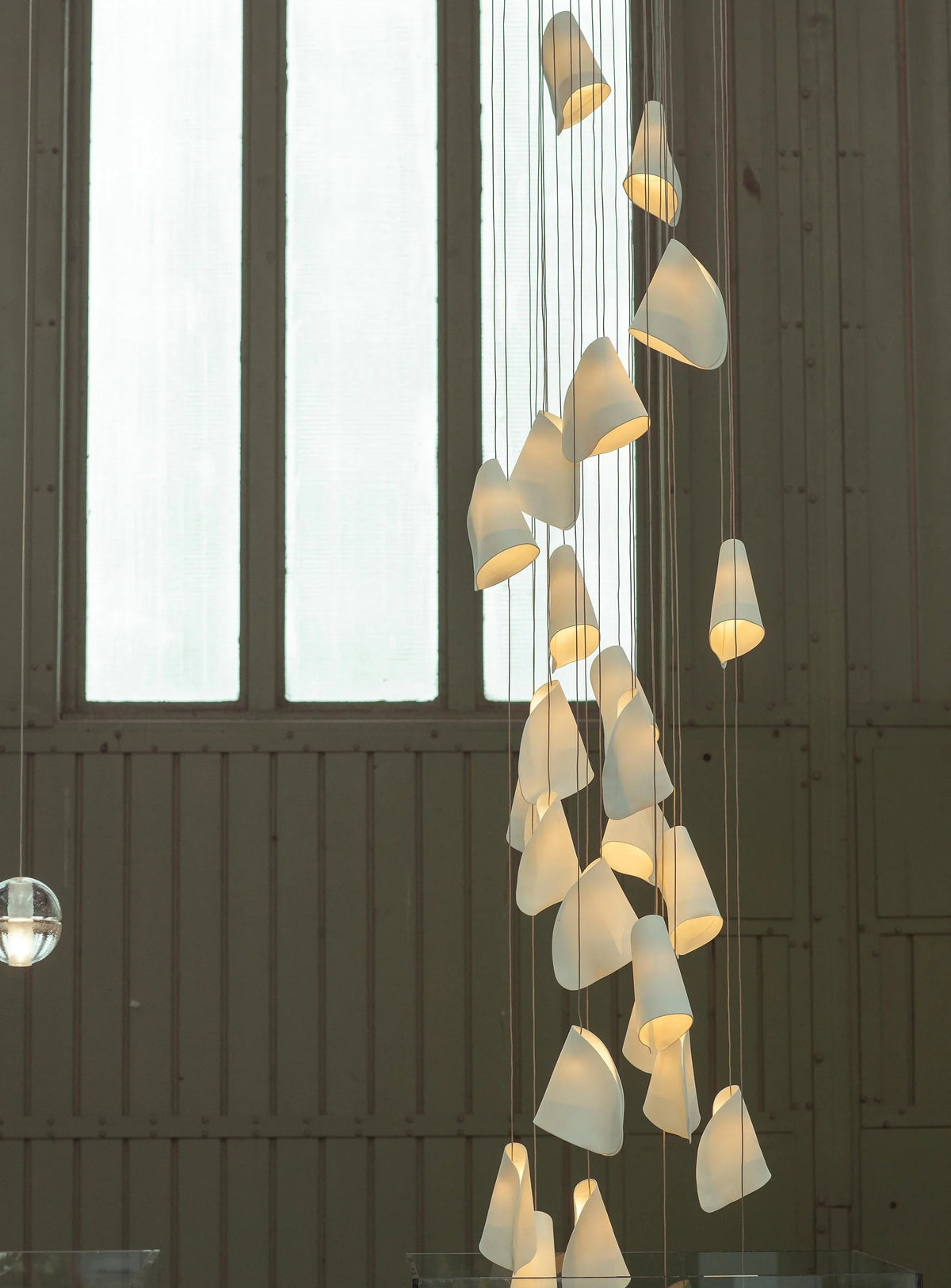 Modern chandelier with glass shades hanging in a room with large windows.