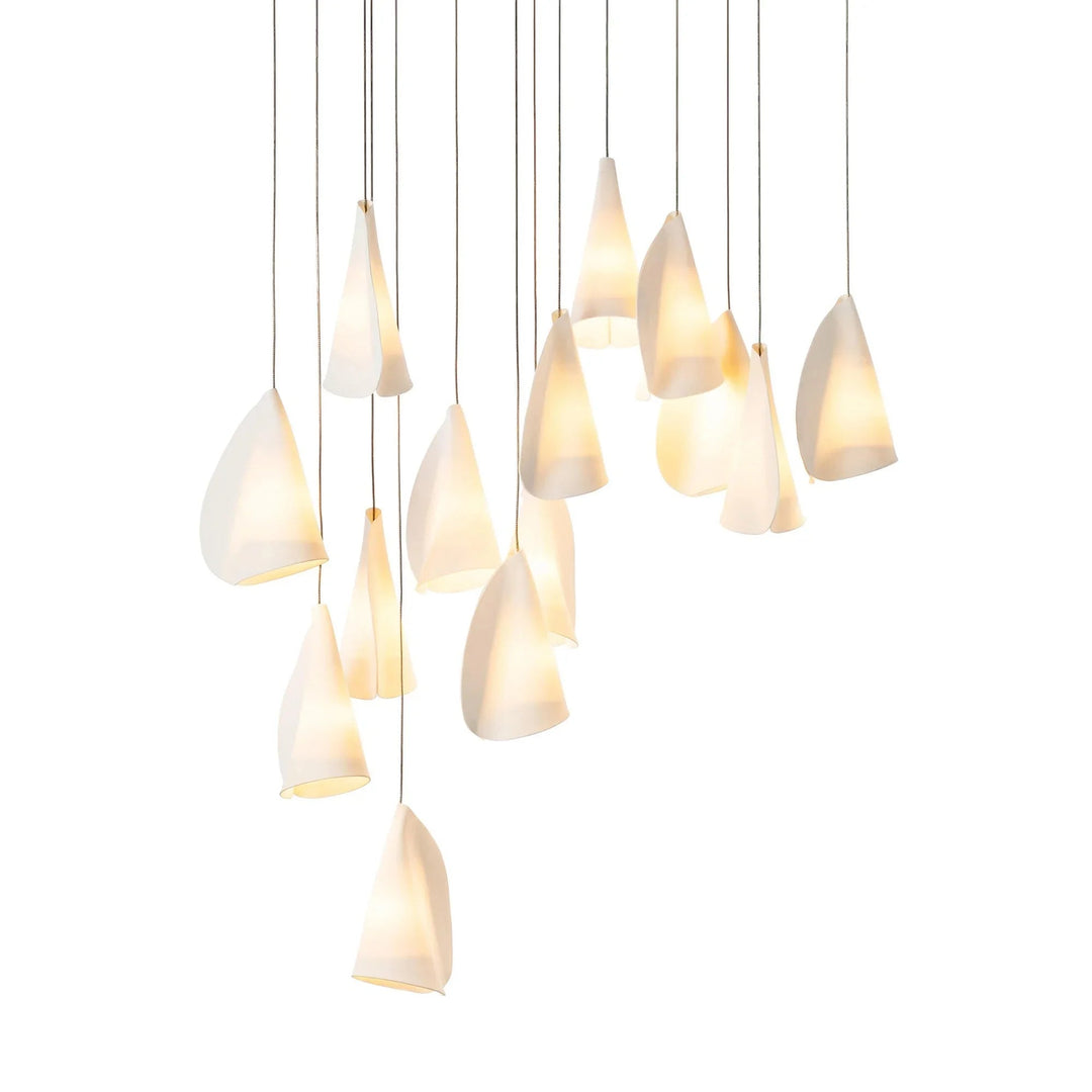 White porcelain chandelier with folded shades glowing at staggered heights on thin dark cords against a white background.