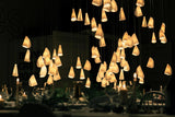 Chandelier hanging above a table setting with candles and glasses in a dimly lit room.