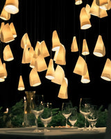 Chandelier with cone-shaped lights over a dining table with wine glasses.
