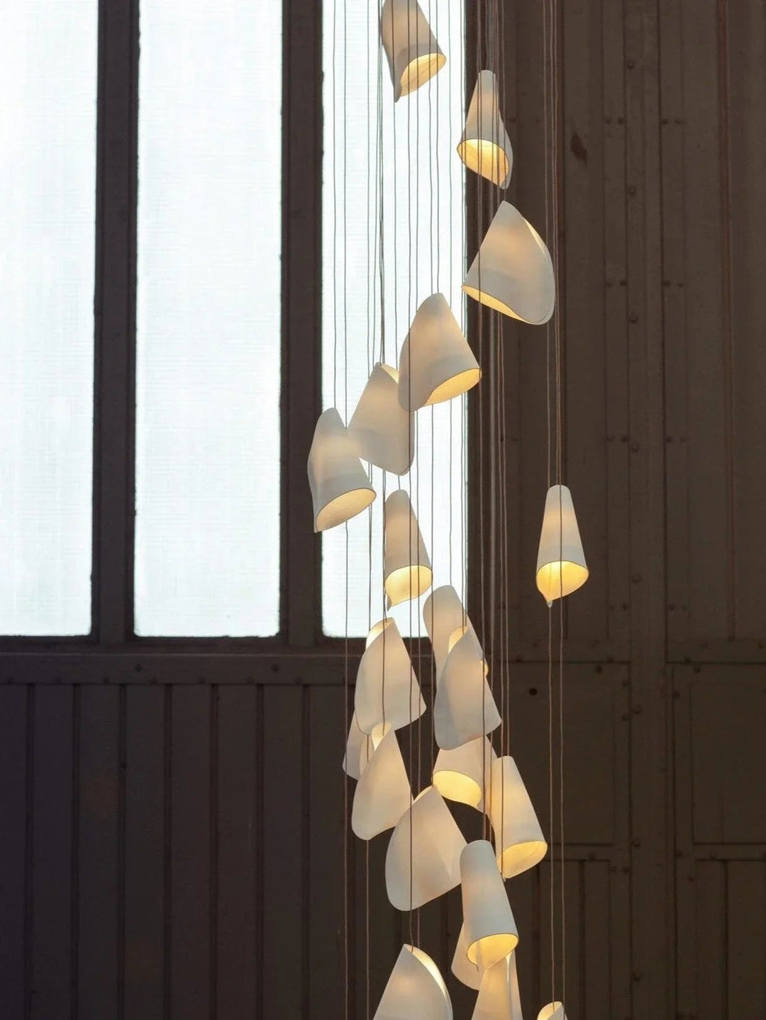 Modern chandelier with multiple hanging lights against a dark wall.
