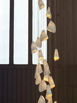 Modern chandelier with multiple hanging lights against a dark wall.