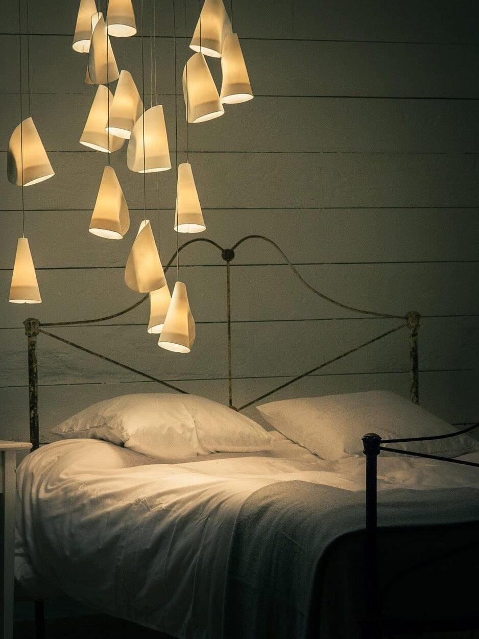 Bedroom with a chandelier casting warm light over a bed with white bedding.
