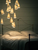 Bedroom with a chandelier casting warm light over a bed with white bedding.