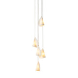 Chandelier with five glowing white porcelain shades hanging in a long staggered arrangement against a white background.