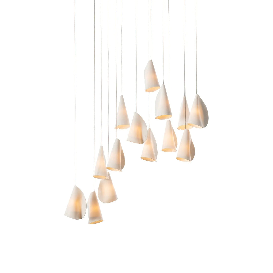 White porcelain chandelier with illuminated folded shades suspended at staggered heights against a white background.