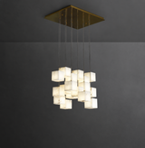 A modern multi-light pendant chandelier with glowing square glass shades suspended from a square brass ceiling canopy against a dark gray wall.