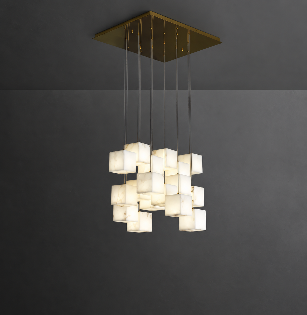A modern multi-light pendant chandelier with glowing square glass shades suspended from a square brass ceiling canopy against a dark gray wall.