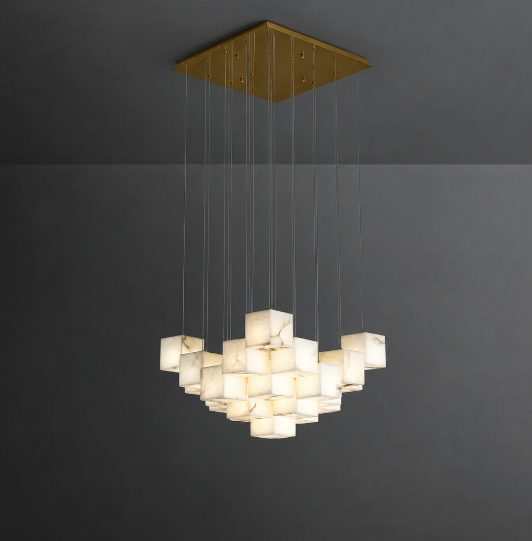 A modern multi-light pendant chandelier with a square gold-toned ceiling canopy and multiple illuminated white marble cube shades suspended by thin cables against a dark gray wall.