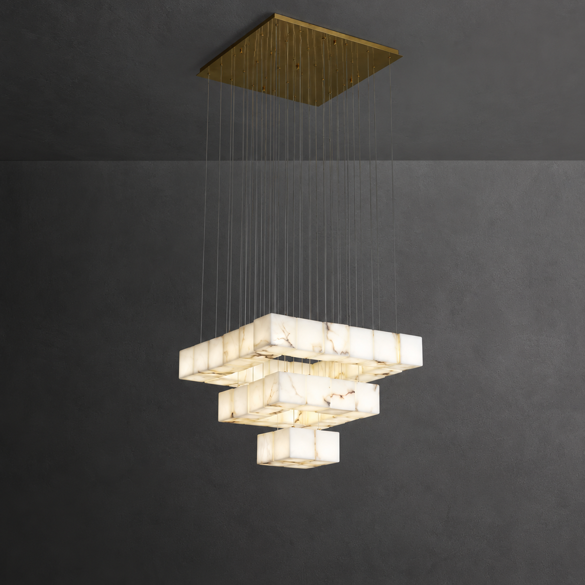 A modern multi-tiered geometric chandelier with white marble-look rectangular shades suspended from a square gold-toned ceiling canopy against a dark gray wall.