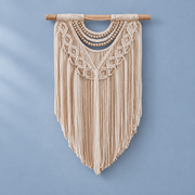 Cream macrame wall hanging with wooden bead swags and a deep V fringe on blue
