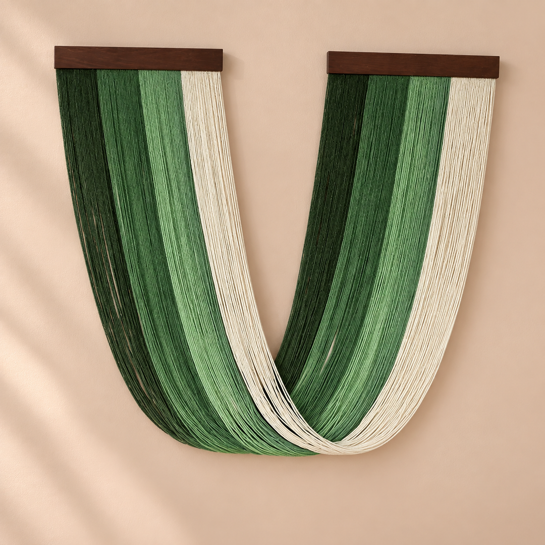 Deep green and cream U swag fringe hanging between two dark battens on sand