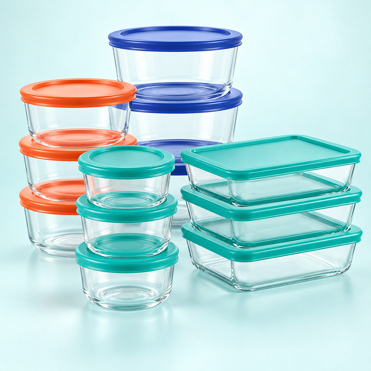 A set of clear glass food storage containers with colorful lids in orange, teal, and blue, arranged on a light blue background.