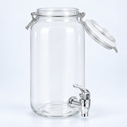 Clear glass canister with an open clamp lid and a silver metal spout, photographed on a clean white background.