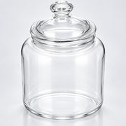 Clear glass jar with a matching glass lid and knob, photographed on a clean light gray to white studio background.