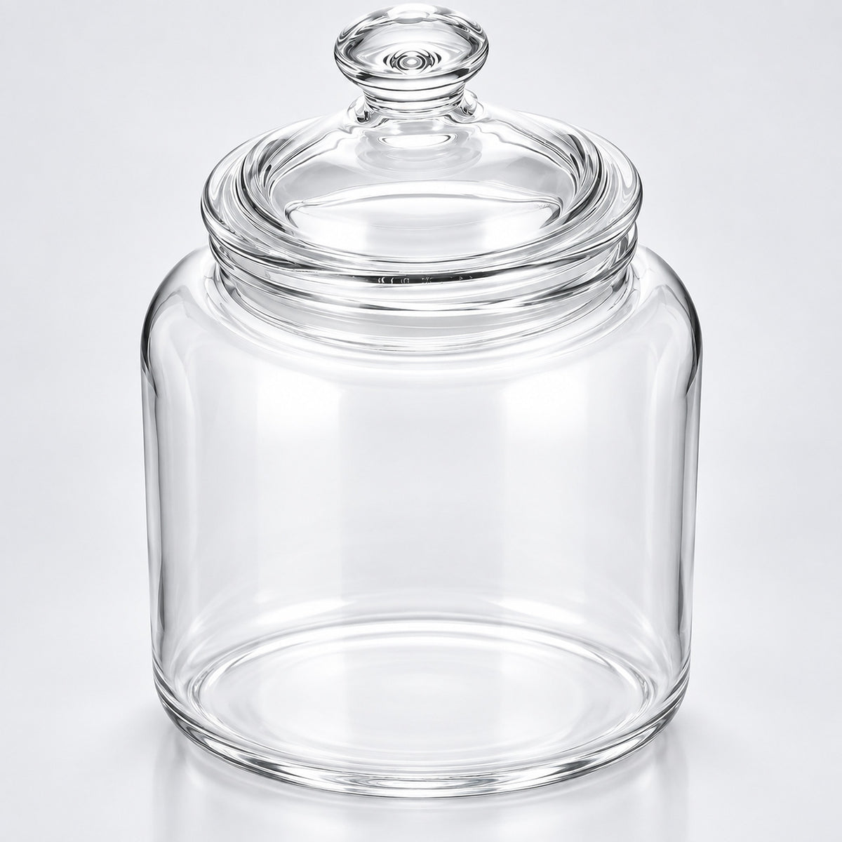 Clear glass jar with a matching glass lid and knob, photographed on a clean light gray to white studio background.