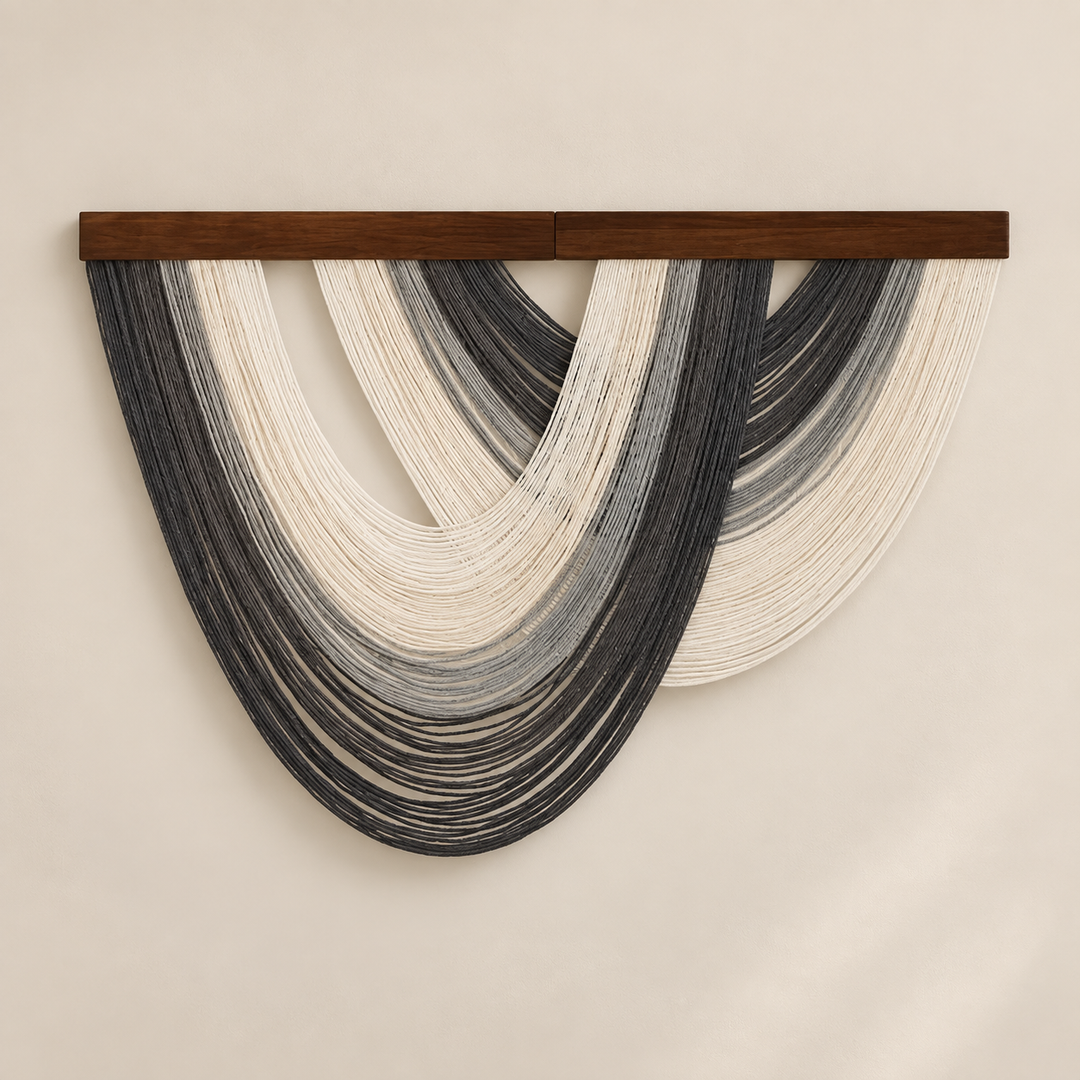 Charcoal and slate open fan wall hanging with a cream center on a pale wall